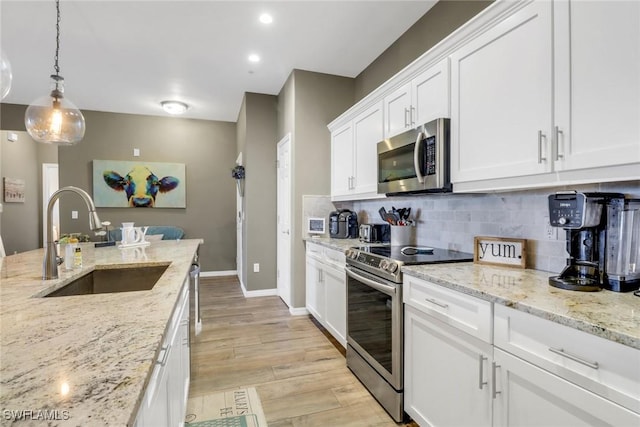 11711 Pasetto Ln Unit 407, Fort Myers, FL 33908 - kitchen featuring appliances with stainless steel finishes, a sink, baseboards, backsplash, and white cabinetry