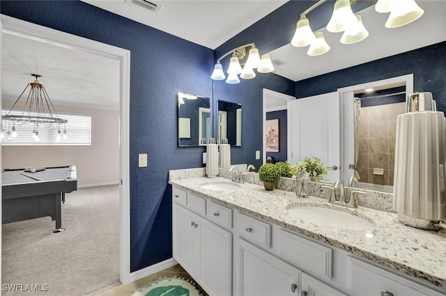 2369 Tangerine Ln, Naples, FL 34120 - full bathroom with a chandelier, baseboards, a textured wall, tiled shower, and double vanity