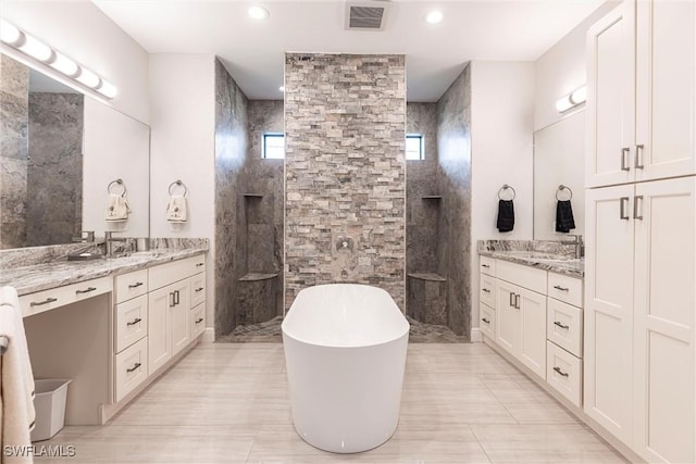 full bathroom with walk in shower, two vanities, a freestanding bath, and recessed lighting