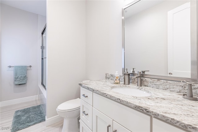 full bath with toilet, vanity, baseboards, wood finished floors, and bath / shower combo with glass door