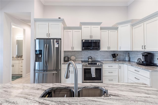 kitchen with stainless steel appliances, crown molding, a sink, and white cabinetry