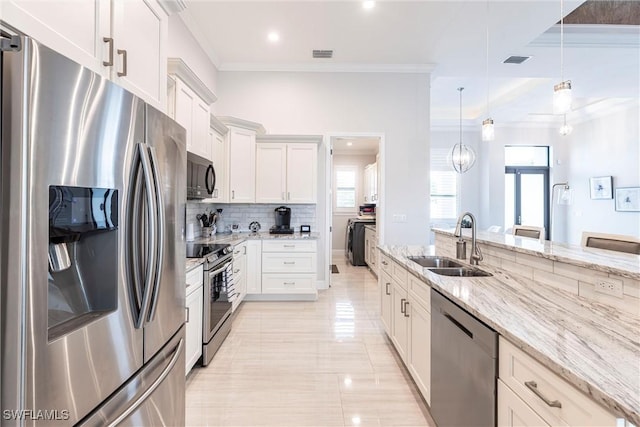 kitchen with appliances with stainless steel finishes, a sink, crown molding, light stone countertops, and washer / dryer