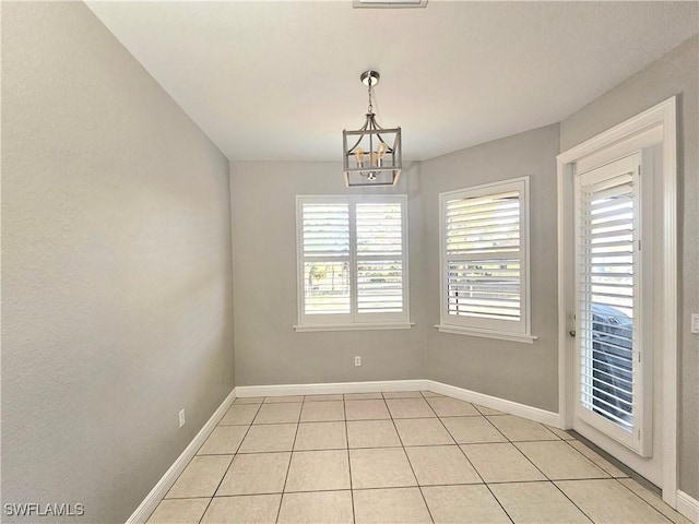 3290 37th Ave NE, Naples, FL 34120 - empty room with a chandelier, plenty of natural light, light tile patterned floors, and baseboards