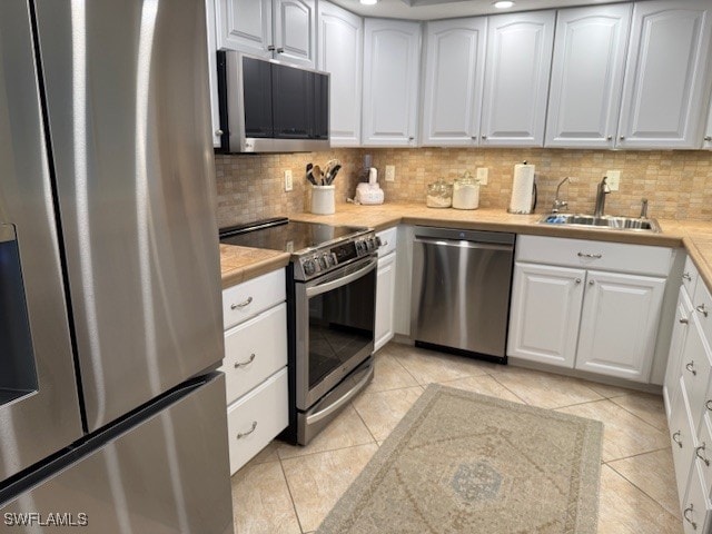 2880 Gulf Shore Blvd N Unit 404, Naples, FL 34103 - kitchen featuring stainless steel appliances, backsplash, light countertops, light tile patterned floors, and white cabinets