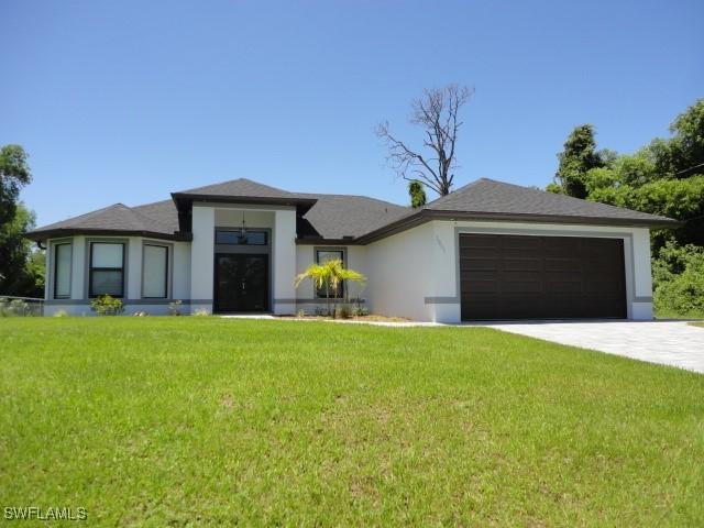 3805 6th St W, Lehigh Acres, FL 33971 - prairie-style house with a garage, stucco siding, a front yard, and driveway