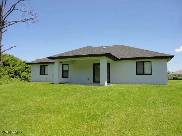 3805 6th St W, Lehigh Acres, FL 33971 - rear view of house featuring a yard, stucco siding, and a shingled roof