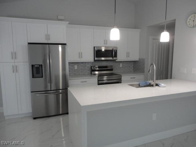 3805 6th St W, Lehigh Acres, FL 33971 - kitchen with stainless steel appliances, light marble finish flooring, a sink, decorative backsplash, and white cabinetry
