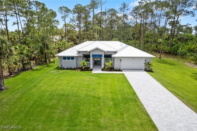 view of front facade with a garage, decorative driveway, a front yard, and stucco siding