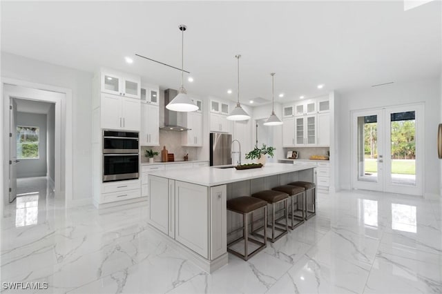 kitchen featuring french doors, appliances with stainless steel finishes, wall chimney range hood, decorative backsplash, and recessed lighting