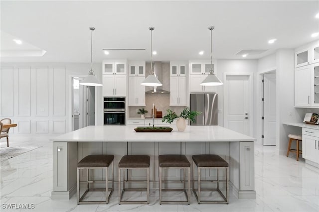 kitchen featuring appliances with stainless steel finishes, wall chimney exhaust hood, light marble finish floors, decorative backsplash, and recessed lighting