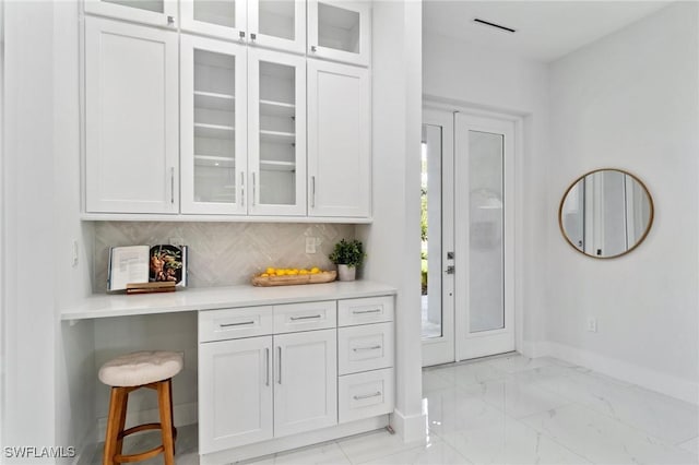 bar featuring baseboards, light marble finish flooring, and backsplash