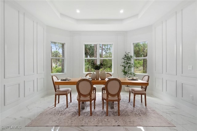 dining space with light marble finish floors, a raised ceiling, and recessed lighting