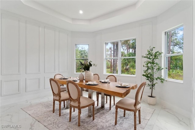dining space with marble finish floors, a tray ceiling, and baseboards