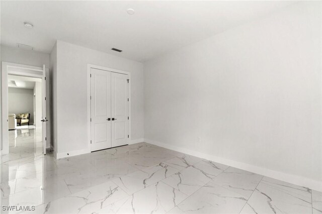unfurnished bedroom featuring baseboards, a closet, and marble finish flooring
