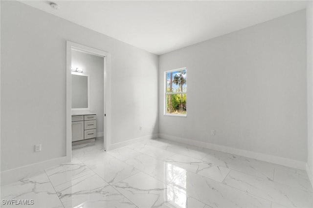 unfurnished bedroom with baseboards, light marble finish flooring, and connected bathroom