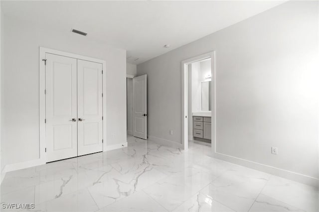 unfurnished bedroom with light marble finish floors, baseboards, a closet, and connected bathroom