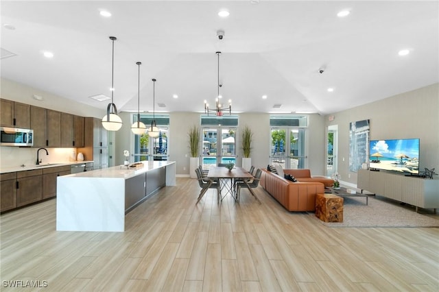 26380 Coco Cay Cir Unit 101, Bonita Springs, FL 34135 - kitchen with stainless steel appliances, light countertops, open floor plan, light wood finished floors, and hanging light fixtures