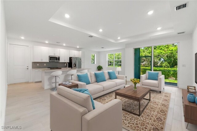 26380 Coco Cay Cir Unit 101, Bonita Springs, FL 34135 - living room featuring a raised ceiling, recessed lighting, and light wood-style floors