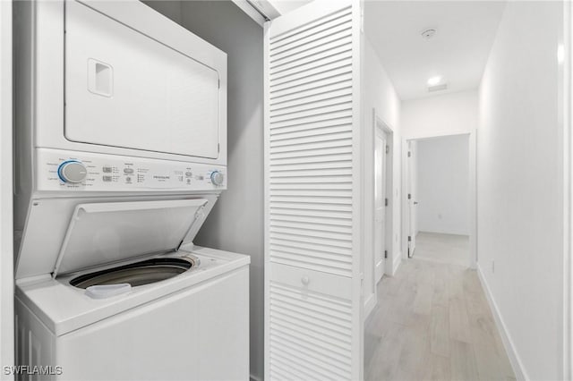 26380 Coco Cay Cir Unit 101, Bonita Springs, FL 34135 - laundry room with stacked washer / dryer, light wood-style flooring, and baseboards
