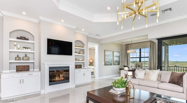 living room with a glass covered fireplace, built in features, a chandelier, ornamental molding, and a raised ceiling