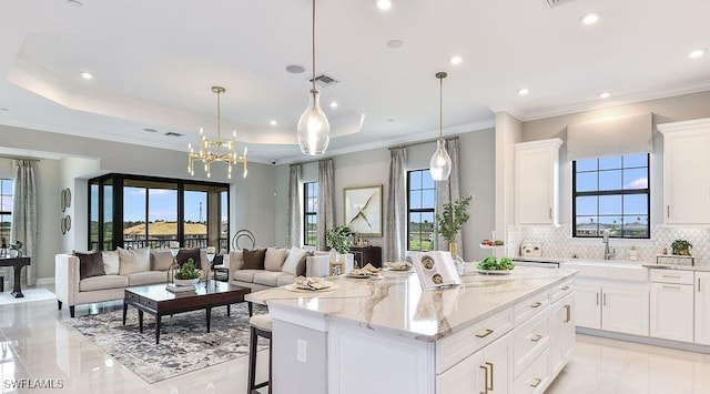 kitchen featuring open floor plan, a sink, a center island, backsplash, and white cabinetry