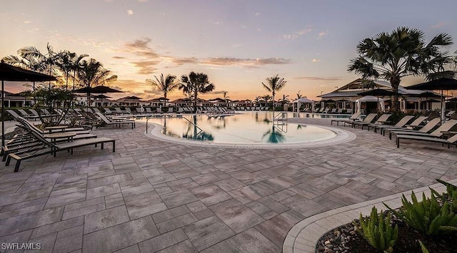 pool at dusk with a community pool and a patio area