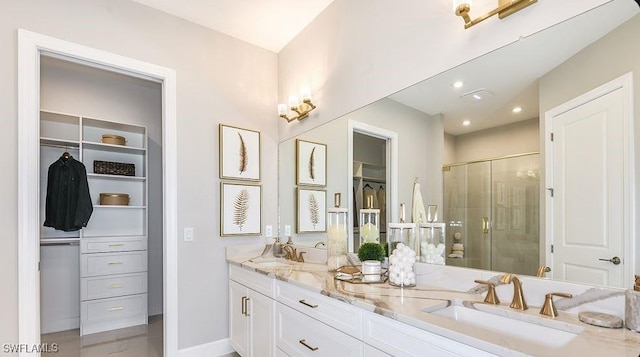full bath with a shower stall, a spacious closet, double vanity, recessed lighting, and baseboards