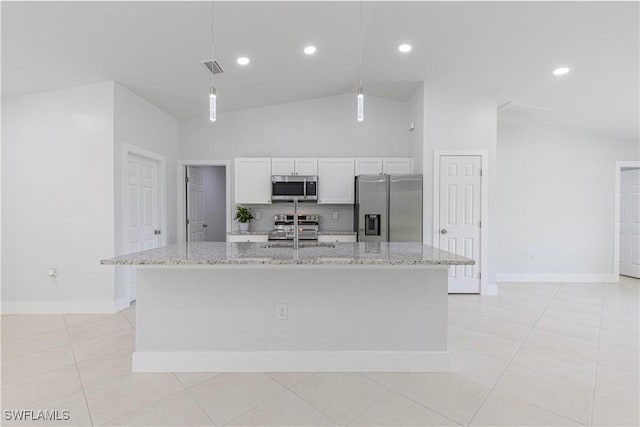 kitchen with appliances with stainless steel finishes, lofted ceiling, backsplash, white cabinets, and an island with sink