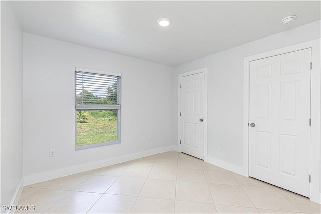 unfurnished bedroom with baseboards, light tile patterned floors, and recessed lighting