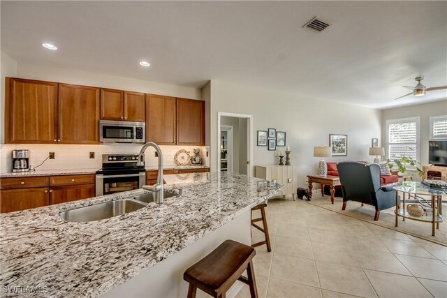 16112 Cutters Ct, Fort Myers, FL 33908 - kitchen featuring stainless steel appliances, a sink, brown cabinets, a kitchen breakfast bar, and recessed lighting