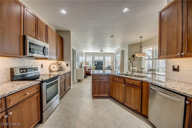 16112 Cutters Ct, Fort Myers, FL 33908 - kitchen with appliances with stainless steel finishes, a sink, open floor plan, a peninsula, and brown cabinetry