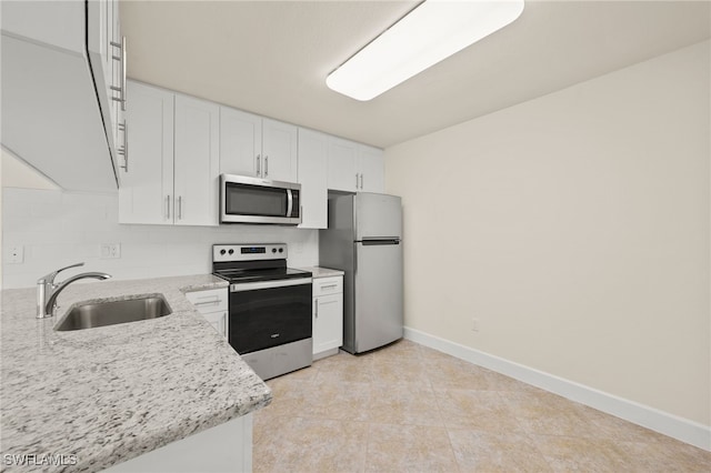 17307 Timber Oak Ln, Fort Myers, FL 33908 - kitchen with stainless steel appliances, a sink, white cabinets, baseboards, and light stone counters