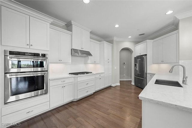 4750 Via Del Corso Ln Unit 201, Bonita Springs, FL 34134 - kitchen featuring stainless steel appliances, a sink, under cabinet range hood, arched walkways, and ornamental molding