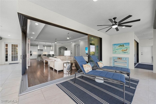 4750 Via Del Corso Ln Unit 201, Bonita Springs, FL 34134 - living room featuring ceiling fan, french doors, light tile patterned floors, arched walkways, and a textured ceiling