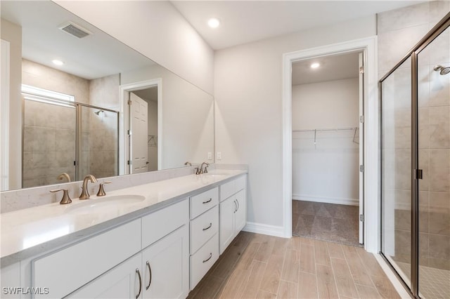16811 Elkhorn Coral Dr, North Fort Myers, FL 33903 - full bath featuring a shower stall, double vanity, a spacious closet, recessed lighting, and wood tiled floors