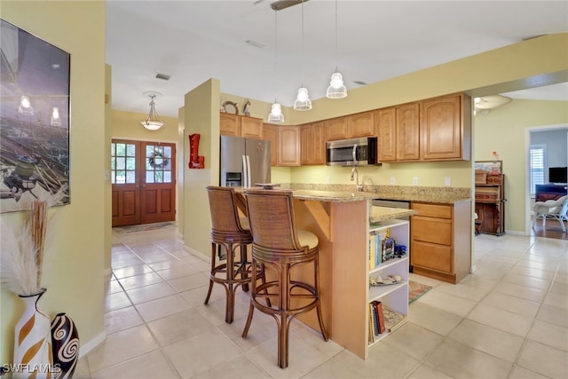 940 Golden Gate Blvd W, Naples, FL 34120 - kitchen with appliances with stainless steel finishes, light tile patterned floors, light stone countertops, a kitchen bar, and hanging light fixtures