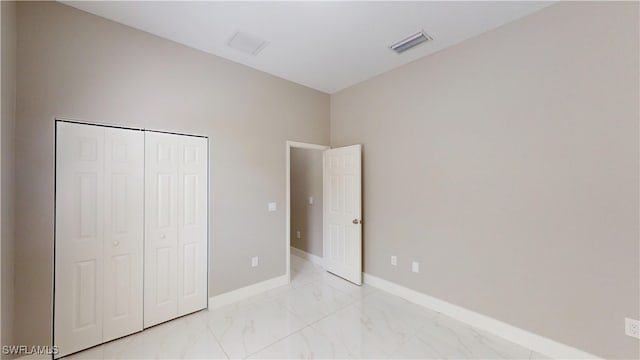 2505 4th St SW, Lehigh Acres, FL 33976 - unfurnished bedroom featuring light marble finish floors, baseboards, and a closet