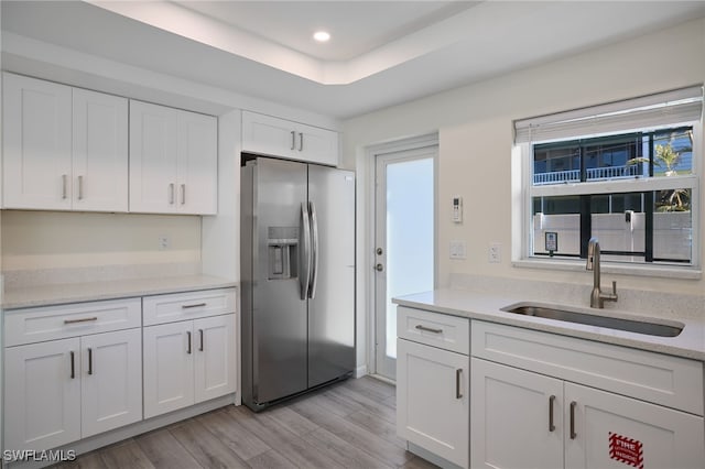 kitchen featuring stainless steel fridge, a sink, white cabinets, light wood-style flooring, and recessed lighting