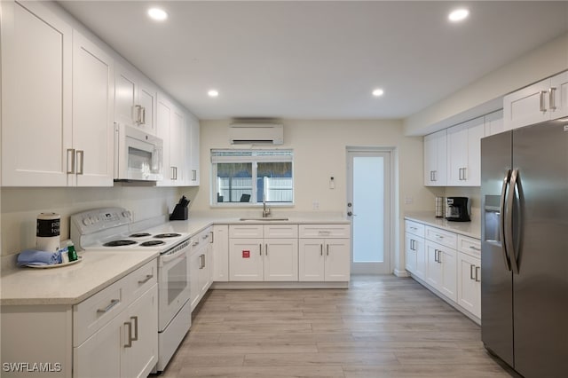 kitchen featuring white appliances, a wall mounted air conditioner, recessed lighting, white cabinetry, and light wood finished floors