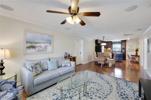 living area with crown molding, dark wood-style flooring, baseboards, and ceiling fan