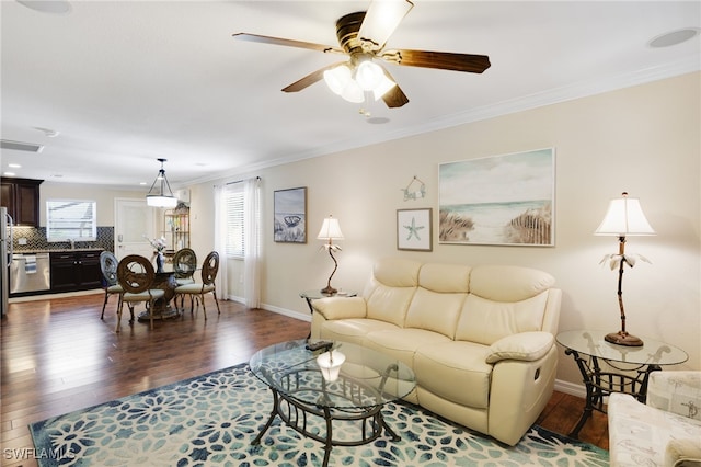 living area with baseboards, dark wood-type flooring, ceiling fan, and ornamental molding