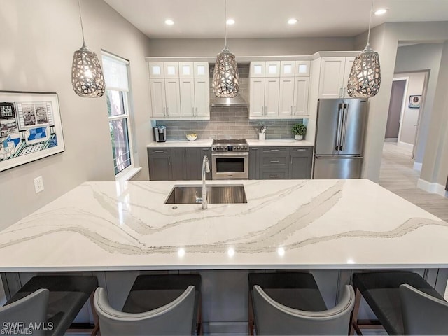 2452 Terra Verde Ln Unit 2452, Naples, FL 34105 - kitchen with high quality appliances, a sink, wall chimney range hood, glass insert cabinets, and recessed lighting