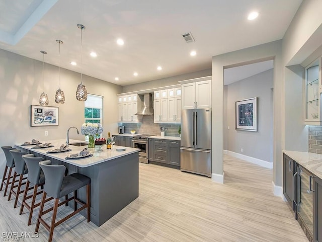 2452 Terra Verde Ln Unit 2452, Naples, FL 34105 - kitchen featuring high end appliances, wall chimney range hood, backsplash, baseboards, and a kitchen bar