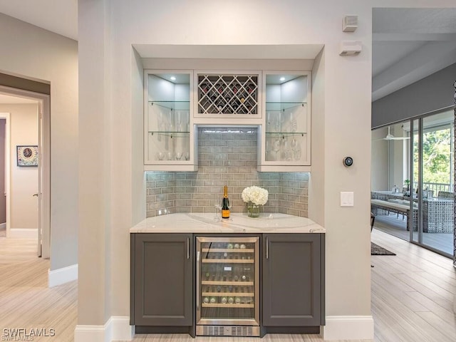 2452 Terra Verde Ln Unit 2452, Naples, FL 34105 - indoor wet bar with beverage cooler, baseboards, backsplash, and light wood-type flooring