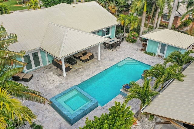 view of swimming pool with french doors, a patio area, outdoor dining area, and a pool with connected hot tub
