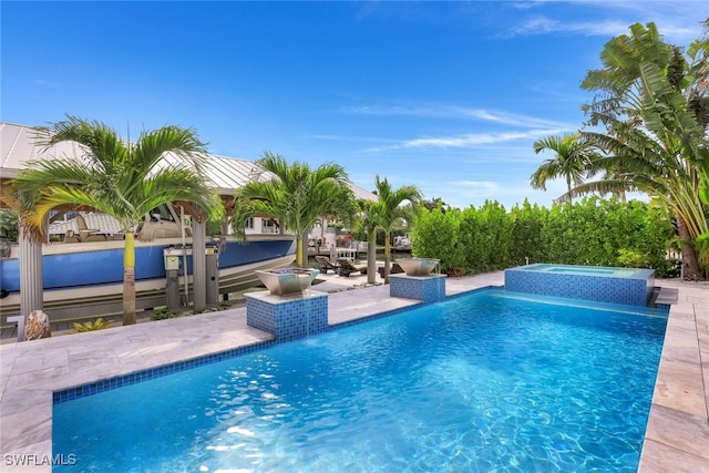 outdoor pool featuring an in-ground hot tub and a patio