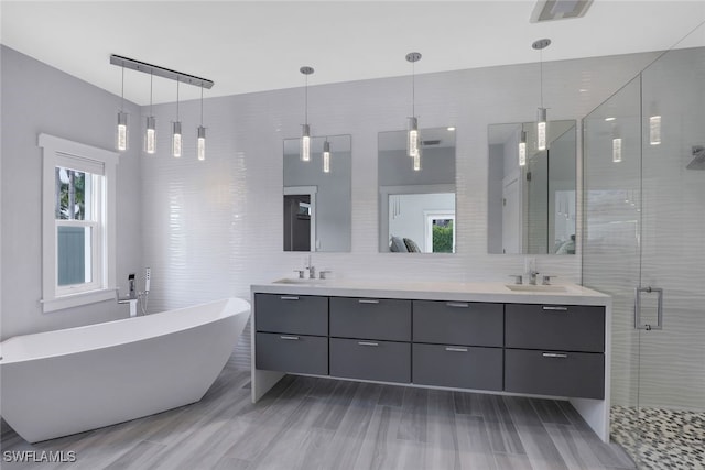 full bathroom featuring double vanity, a shower stall, a freestanding bath, backsplash, and tile walls