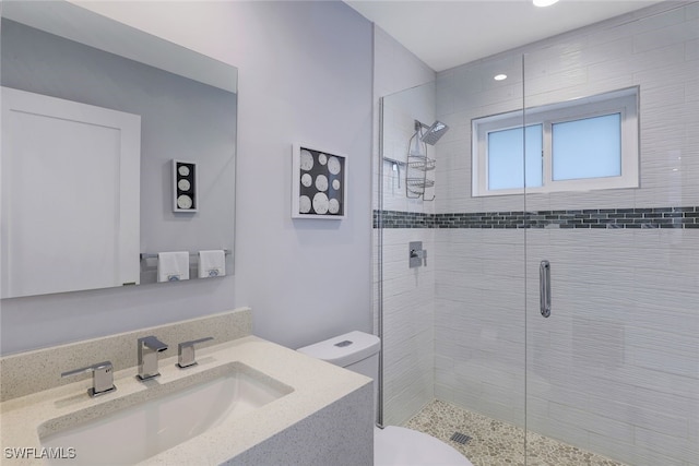 bathroom featuring toilet, a stall shower, and vanity