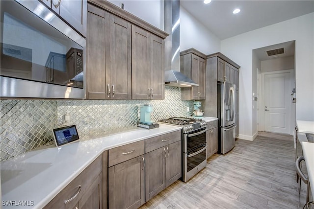 3726 Ceitus Pkwy, Cape Coral, FL 33991 - kitchen with stainless steel appliances, wall chimney exhaust hood, light wood-style floors, light countertops, and tasteful backsplash