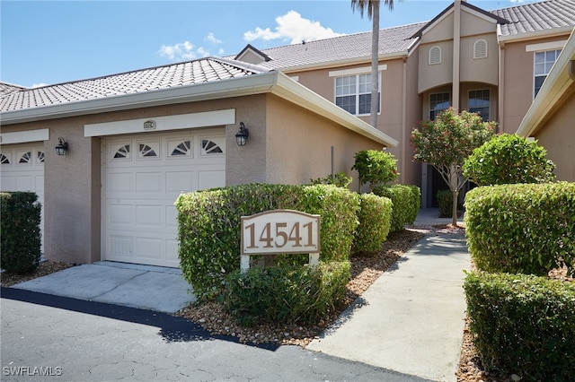 14541 Daffodil Dr Unit 1702, Fort Myers, FL 33919 - view of front of home featuring a tile roof, stucco siding, a garage, and driveway
